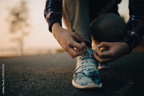 young woman tying her shoelaces at sunset. © stcom