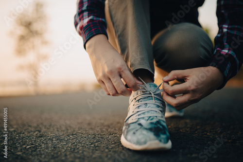 young woman tying her shoelaces at sunset. © stcom