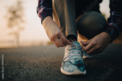 young woman tying her shoelaces at sunset.