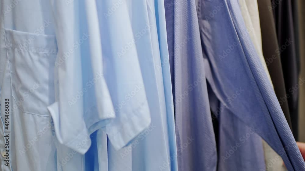close-up female hands sorting blue shirts on a hanger close-up female hands sorting blue shirts on a hanger