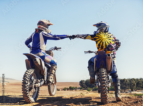 Fototapeta Naklejka Na Ścianę i Meble -  Time to rip up this track. Two motocross riders bumping fists before a race.