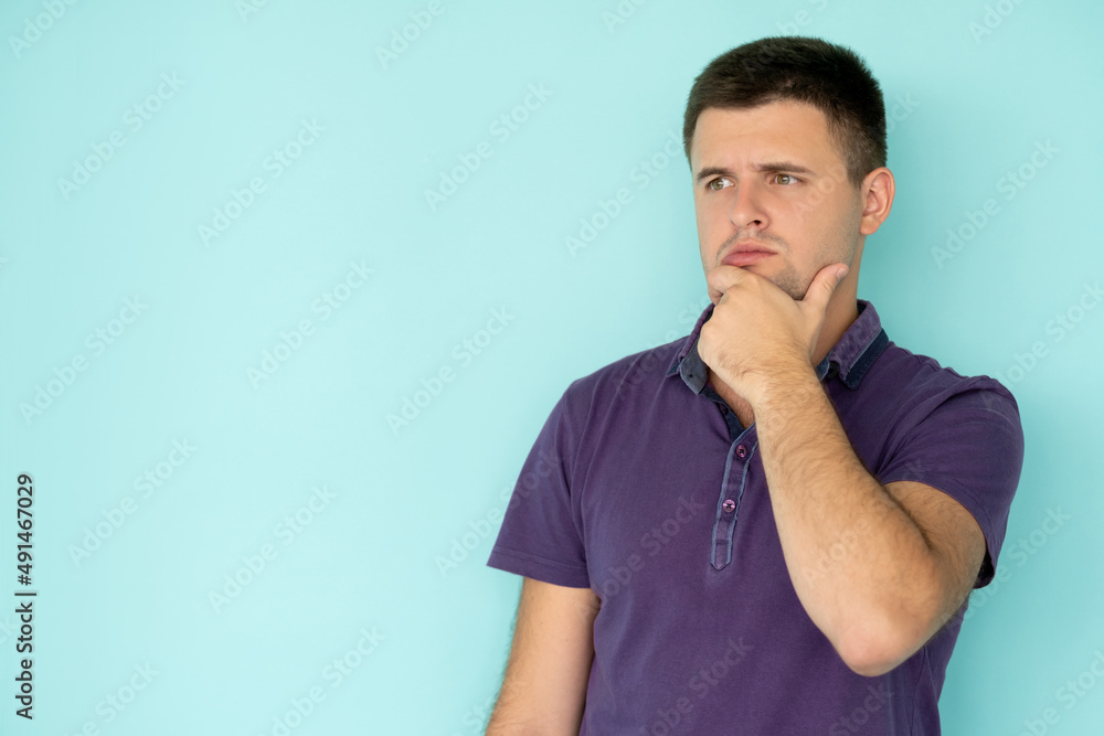 Choice problem. Puzzled man. Confusion idea. Thoughtful handsome guy in casual t-shirt pondering holding hand on chin isolated blue copy space. Choice problem. Puzzled man. Confusion idea. Thoughtful handsome guy in casual t-shirt pondering holding hand on chin isolated blue copy space.