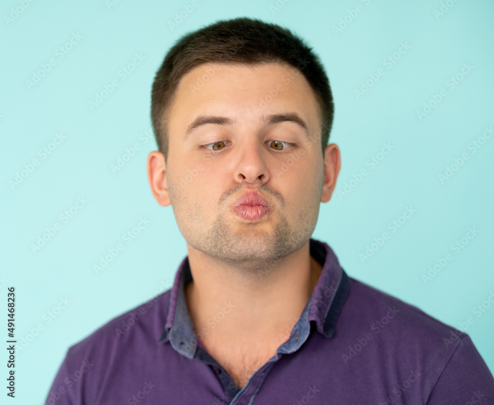 Fototapeta premium Silly man. Ridiculous face. Playing fool. Clueless guy in t-shirt shifting eyes to nose looking squint pouting lips isolated blue.