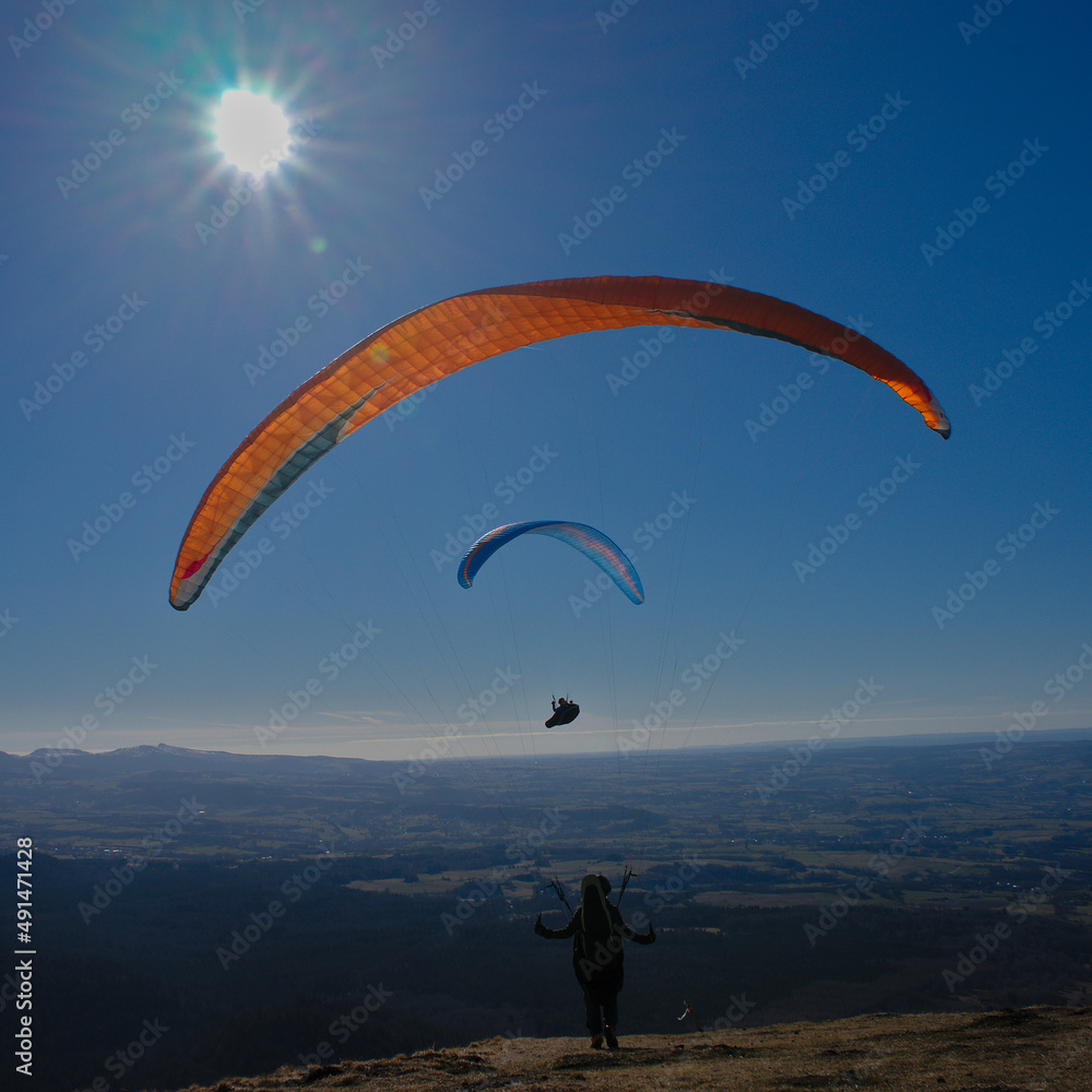 paragliding flight as a couple facing the sun against a background of blue sky in Auvergne paragliding flight as a couple facing the sun against a background of blue sky in Auvergne
