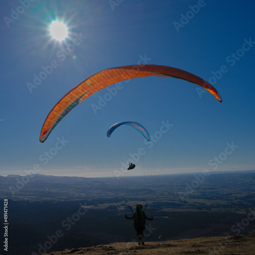 paragliding flight as a couple facing the sun against a background of blue sky in Auvergne