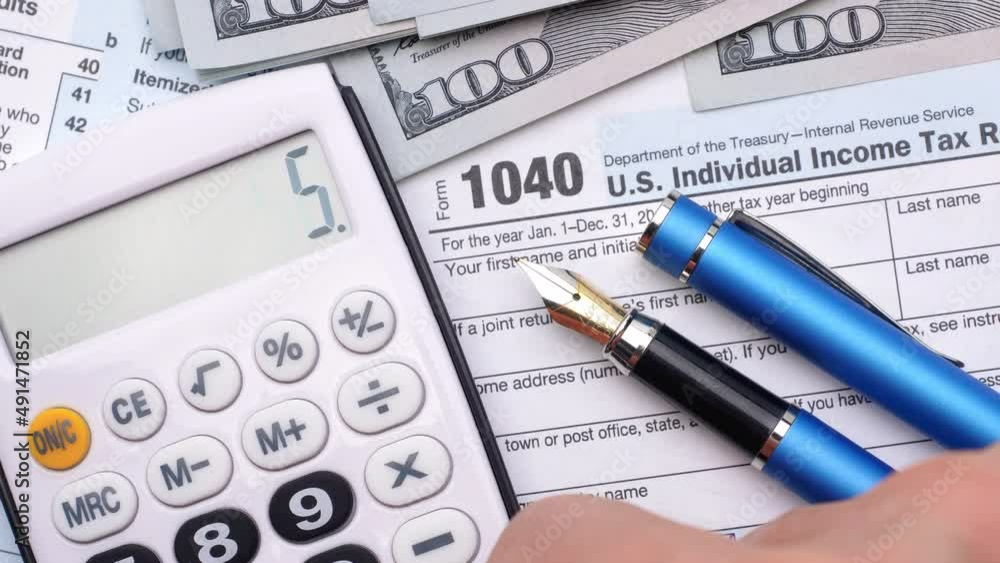 Tax form 1040, pen, dollar bills, and calculator. High angle view. Tax form 1040, pen, dollar bills, and calculator. High angle view.