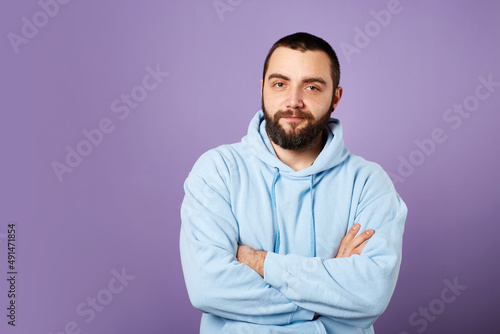 Happy bearded man wears blue sweater on violet background. friendly smile. Copy space