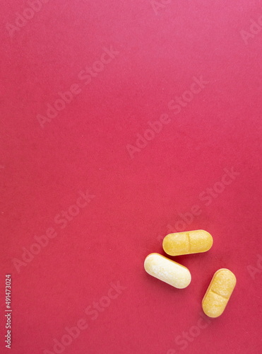 Different pills are on the red table. Background for a medical-themed design with space for text.