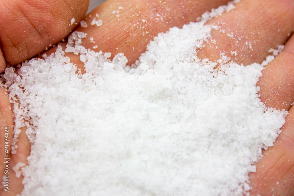 Fototapeta premium Seasoning salt. Salt is natural. Salt in a wooden box. Salt and hands.