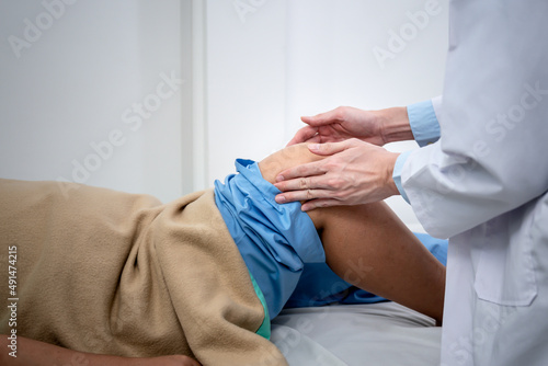 Doctor holding the knee of a female patient lying on the bed, to check the bones and knee injuries, to people health care and Osteoarthritis concept.