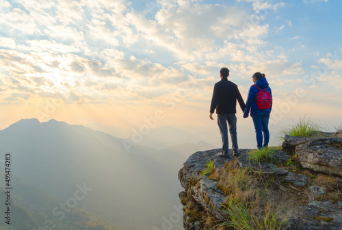 Portrait of an Asian couple, tourists, travel on green mountain hills with fog on holiday vacation. Nature landscape background, Thailand. People lifestyle.