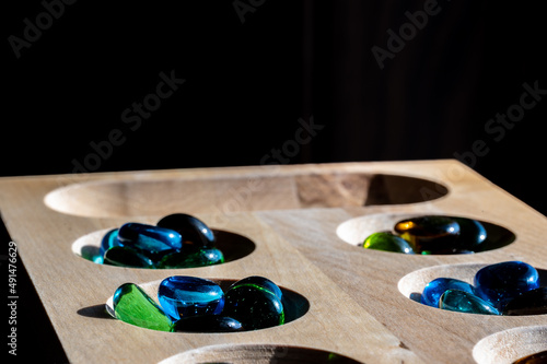 Selective focus on glass beads on a wooden mancala board photo