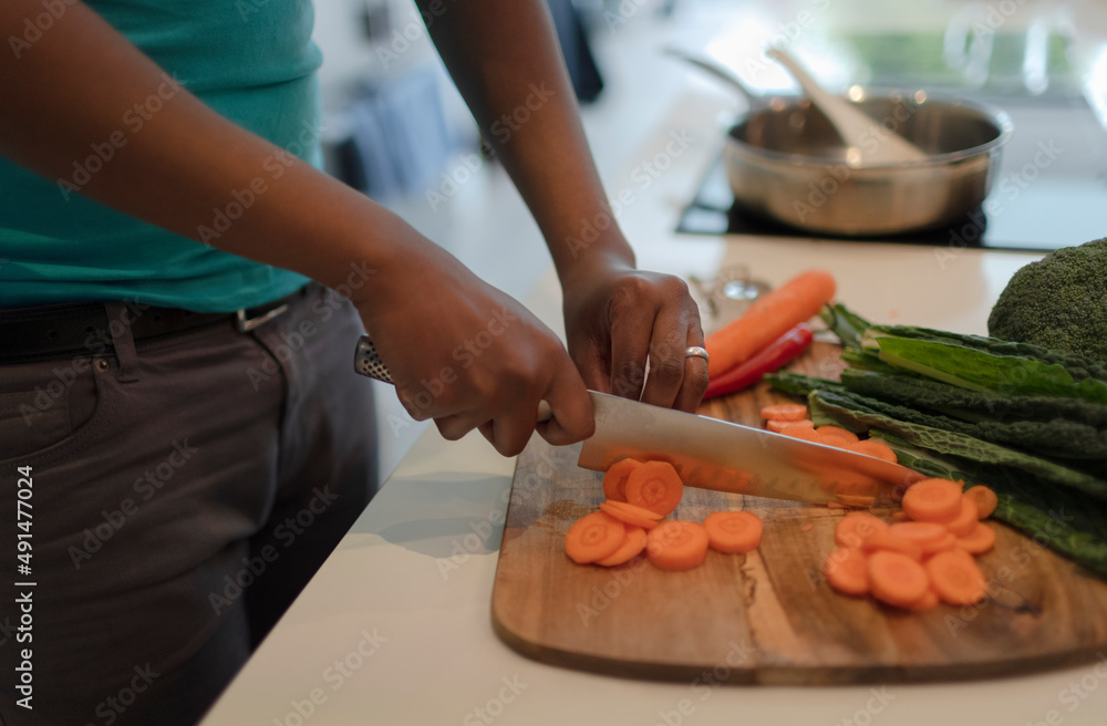 Close up man slicing fresh carrots with butcher knife at cutting board Close up man slicing fresh carrots with butcher knife at cutting board