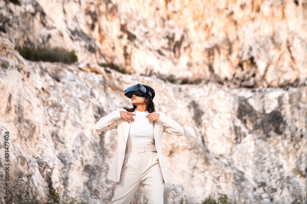 Fototapeta premium Una elegante mujer vestida con un traje blanco usando unas gafas de realidad virtual