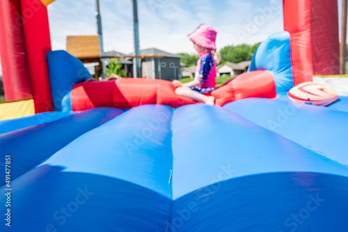 Fototapeta Selective focus on foreword edge of a bouncy house with blurred children playing