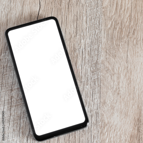 Square photo moke up smartphone on wooden background and copy space. A phone with a white screen on a flat lay desk.