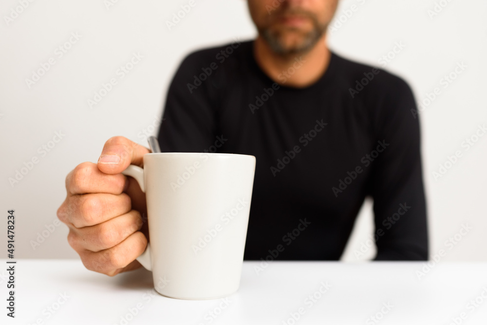 Out of focus man in the background grabs a cup blank on a white table. Out of focus man in the background grabs a cup blank on a white table.