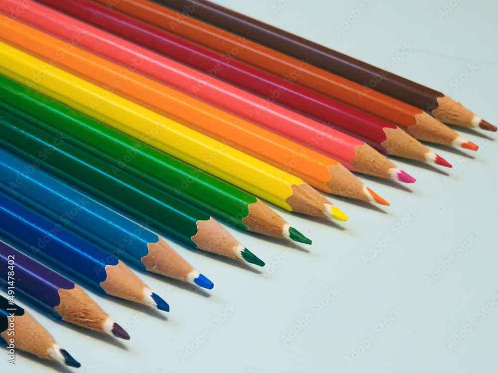 Fototapeta premium Diagonal view of a row of colored pencils over a blue background. Colour crayons.