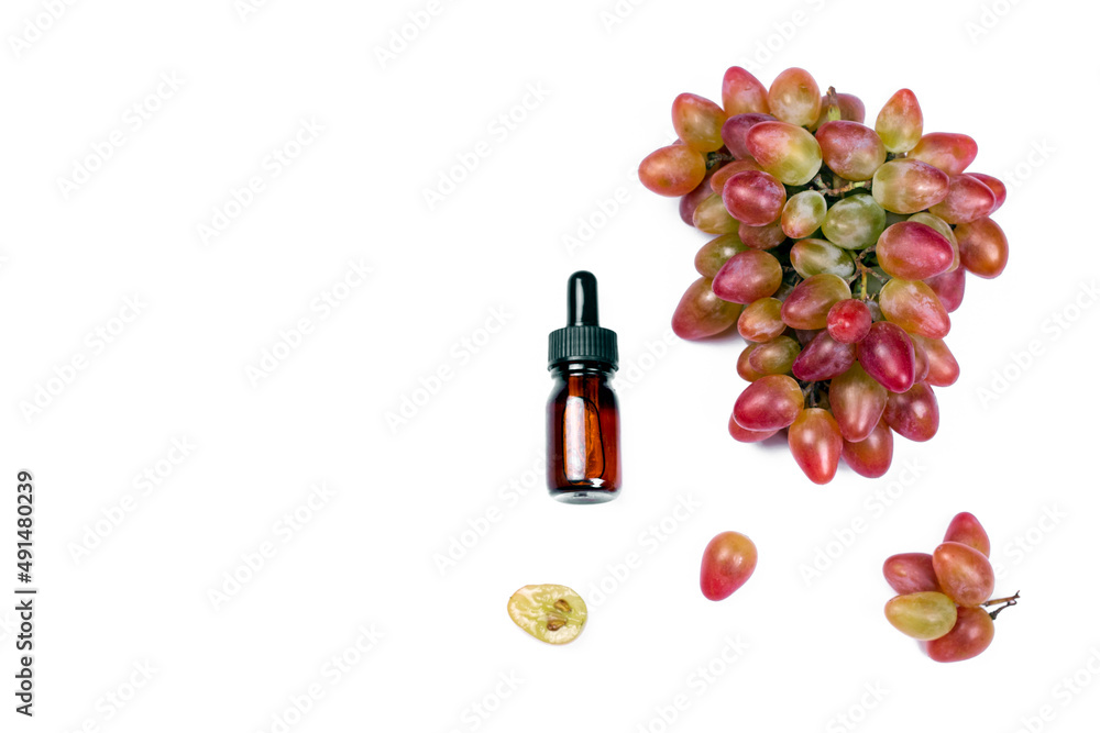 Obraz premium Bottle of grape seed oil or serum and bunch of grapes on white isolated background. Organic Bio cosmetic flat lay, top view image