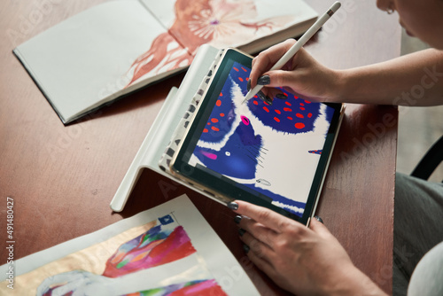Female illustrator sitting at the table and drawing creative pictures at the tablet photo