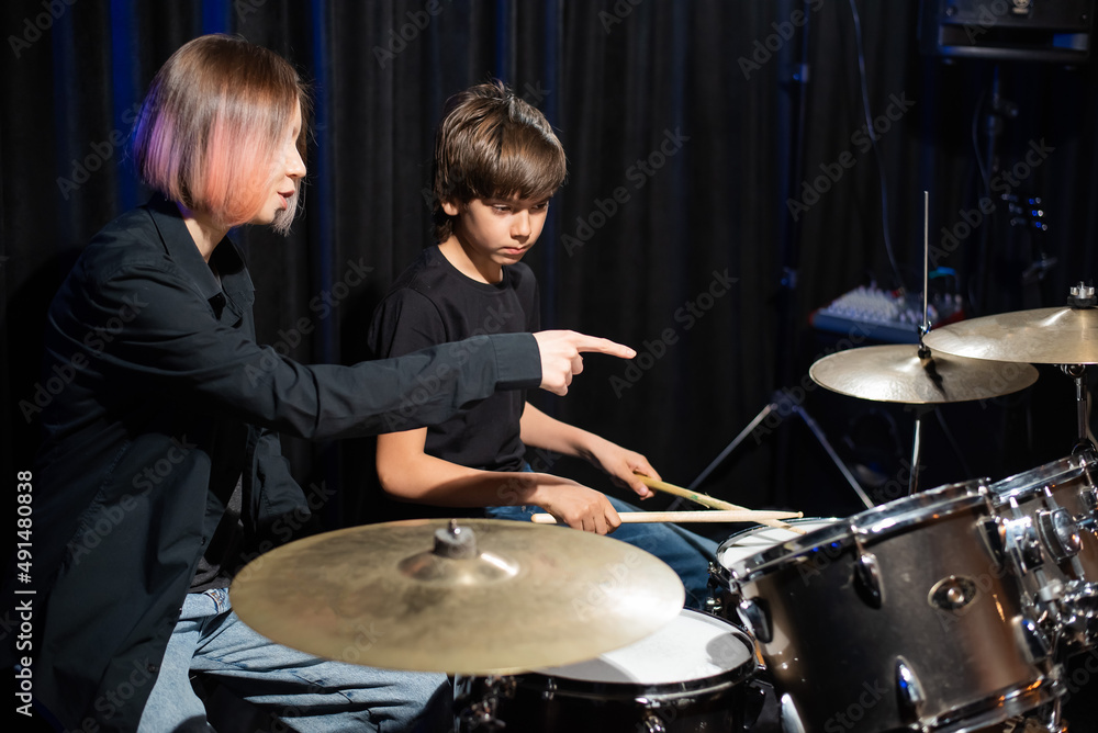 Obraz premium Young woman teaching boy to play drums.
