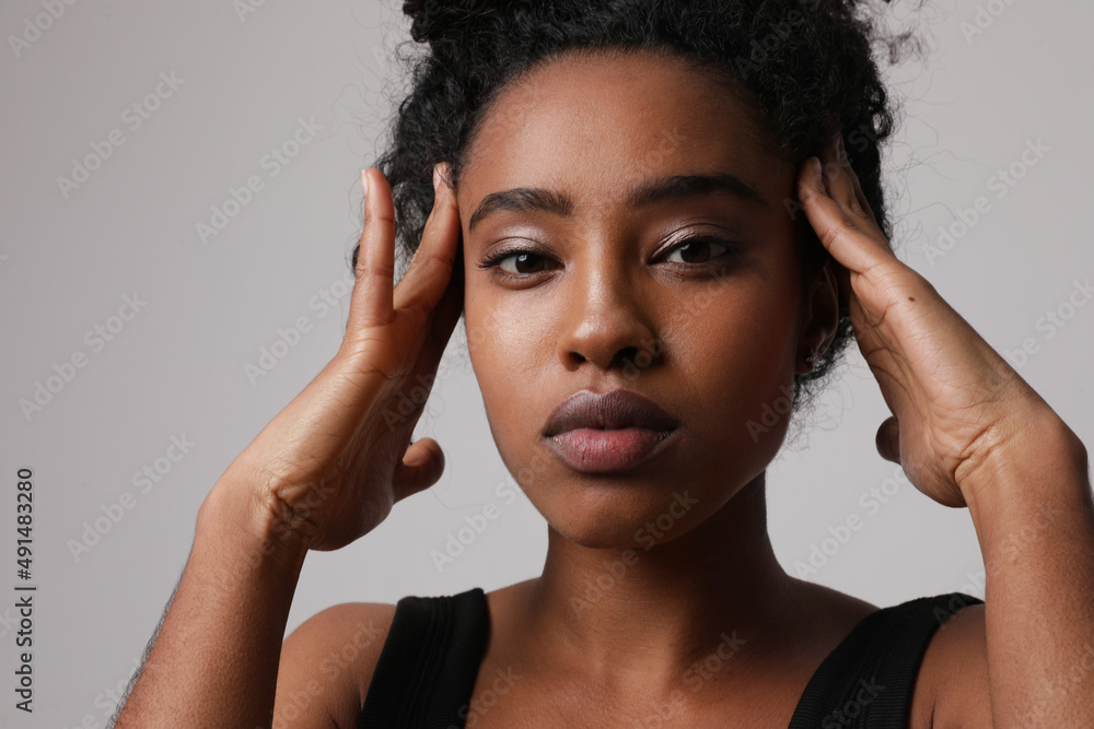 Obraz premium Headshot of African American woman touches her head and looking at the camera.