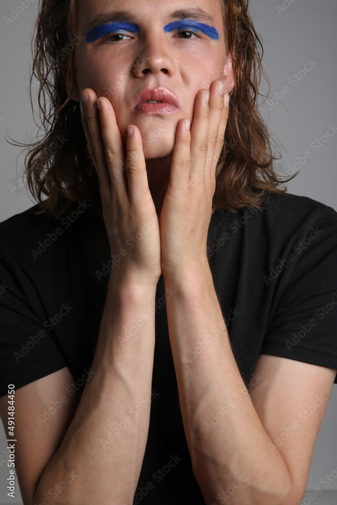 Vertical close-up portrait of a young man with make up and long hair in studio. Vertical close-up portrait of a young man with make up and long hair in studio.