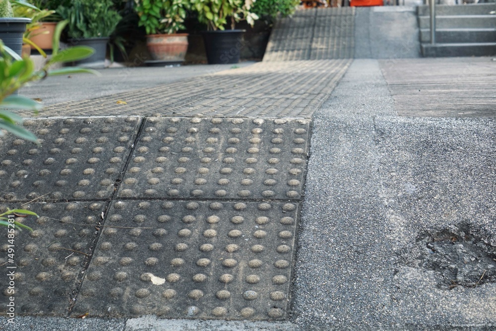Fototapeta premium The sloped sidewalk is lined with braille blocks to provide added convenience and safety for the visually impaired.