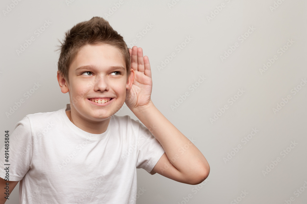 caucasian young boy dressed in the white t-shirt listening through the silence caucasian young boy dressed in the white t-shirt listening through the silence