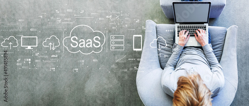 SaaS - software as a service concept with man using a laptop in a modern gray chair