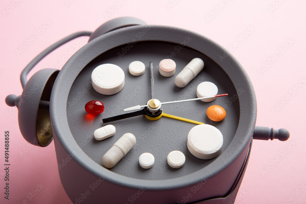 Creative healthcare and medicine concept - clock with drugs and pills.Right time for using medicines. Cold and flu season. Period of diseases Creative healthcare and medicine concept - clock with drugs and pills.Right time for using medicines. Cold and flu season. Period of diseases