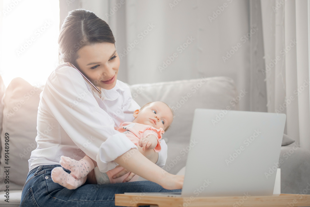Concept freelance life style maternity leave. Beautiful young mother with baby girl working at home office using laptop computer, sun light Concept freelance life style maternity leave. Beautiful young mother with baby girl working at home office using laptop computer, sun light