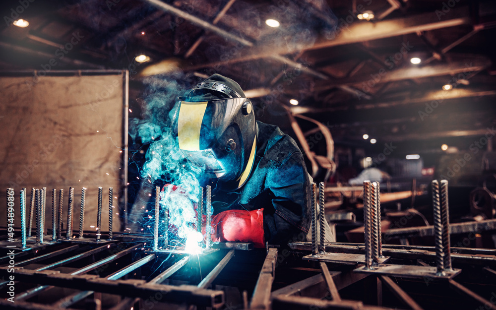 Factory industrial weld worker in workplace with spark. Professional welder erecting metal steel