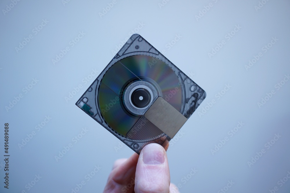 Caucasian fingers holding a minidisc. Blank minidisc. Vintage tech. Retro tech. Stock Photo