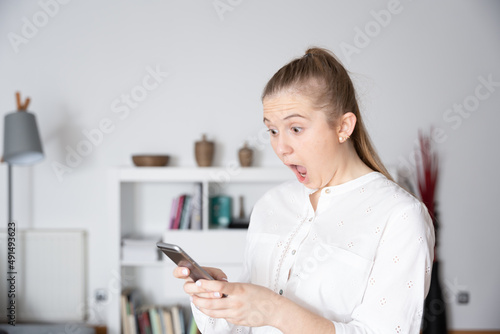 Young woman getting in shock while looking her phone. Bad results on cryptocurrency or stock market concept