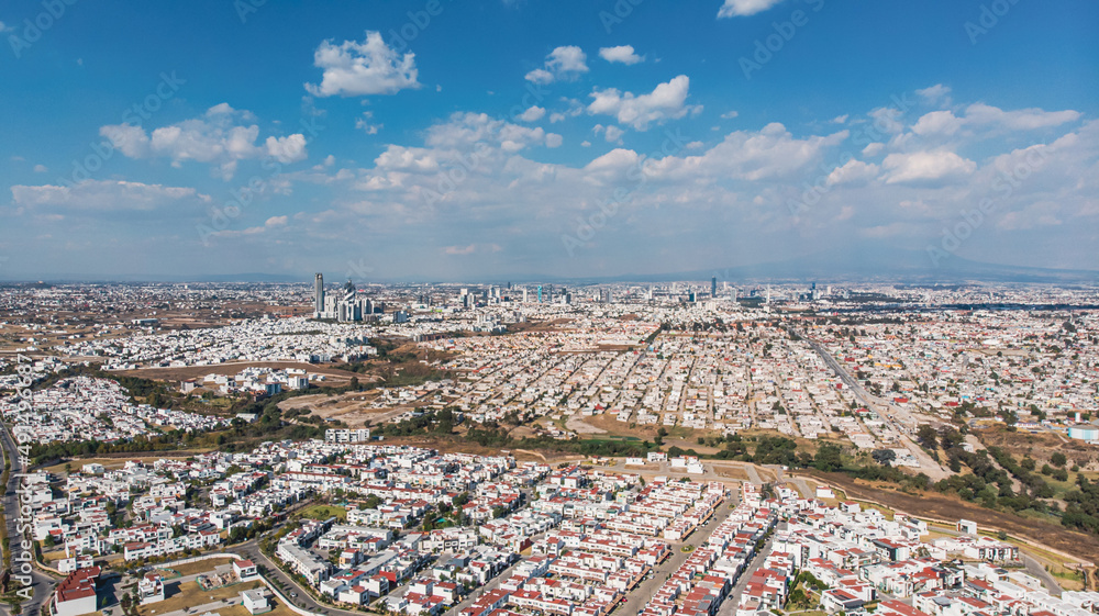 Vista aérea de la ciudad de Puebla, México durante la tarde. Paisaje urbano de casas con el cielo azul.