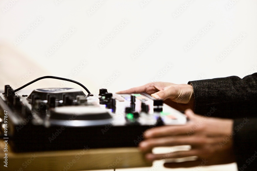 A view of a dj mixer and decks with headphones. Close-up of arms of Dj playing and mixing a track on dj controllers. Disc jockey playing music at the party. Professional DJ works on the equipment. A view of a dj mixer and decks with headphones. Close-up of arms of Dj playing and mixing a track on dj controllers. Disc jockey playing music at the party. Professional DJ works on the equipment.