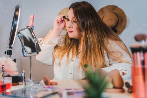 plus size woman making a vlog about cosmetics, painting her eye