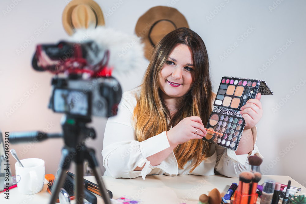 Fototapeta premium Portrait of Caucasian woman reviewing giveaway product to follow fan channel, shooting cosmetic makeup video at home. Online influencer girl social media marketing