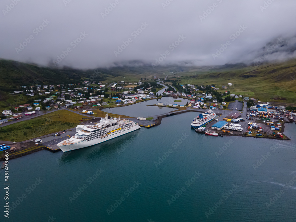 Fototapeta premium Beautiful aerial view of the town of Seydisfjordur and its Blue church and rainbow street, pier and cruise ships