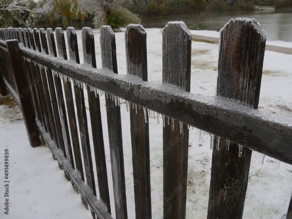 Line of wooden fence with icicles hanging underneath a bar