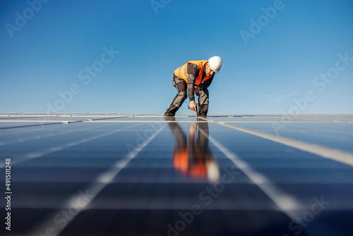 A worker installing solar panels on the rooftop.