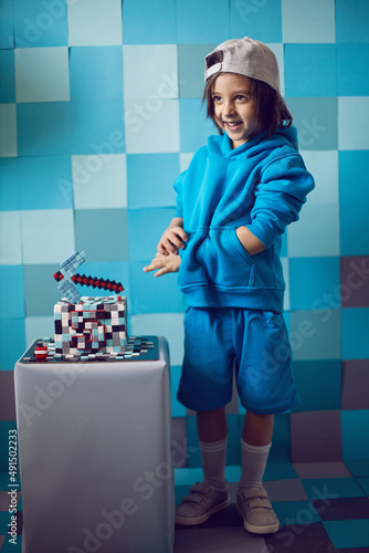 Wall Mural fashion boy in blue clothes bites at a cake pixels with pickaxe in the studio