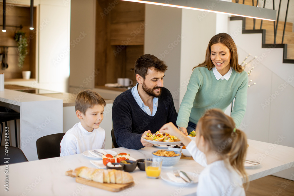 Young happy family talking while having breakfast at dining table Young happy family talking while having breakfast at dining table