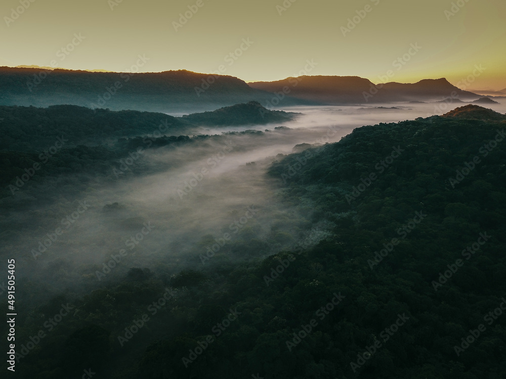 Obraz premium Flying over a mountainous sunrise filled with mist and a beautiful dawn