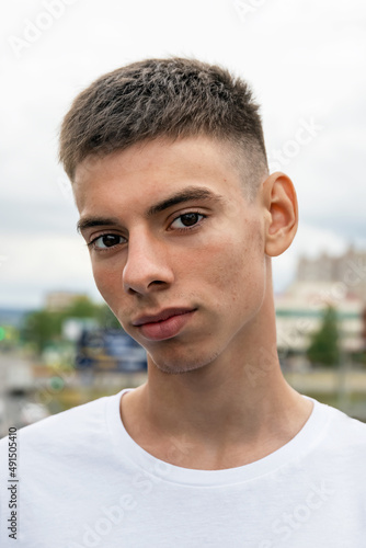 portrait of caucasian handsome teenager with pimples on his face on the outdoor, acne treatment in adolescents