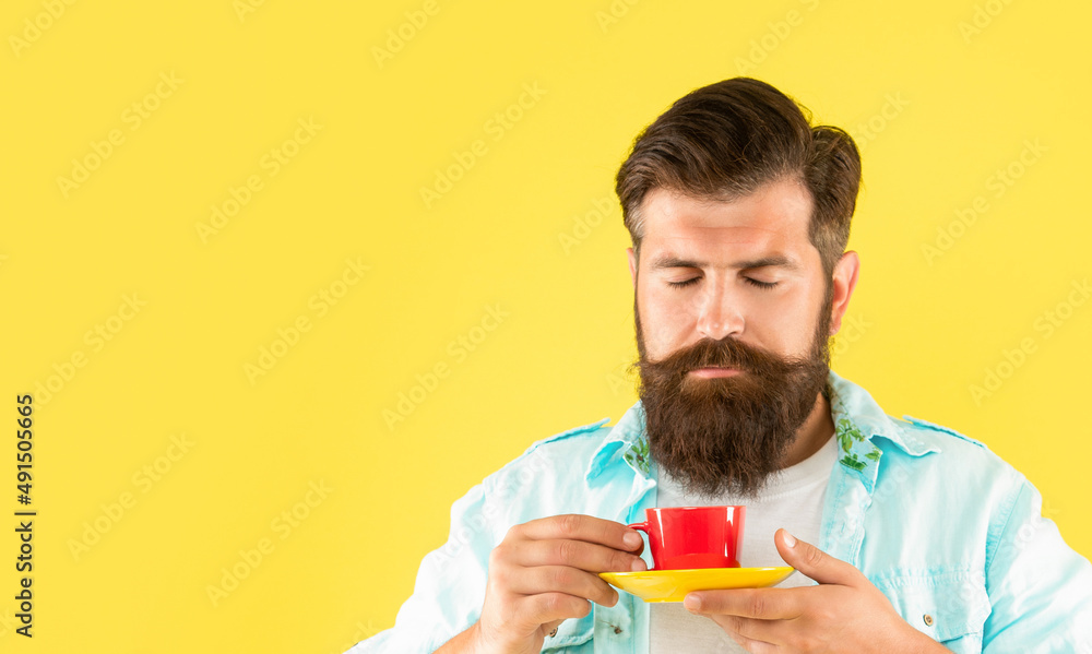 Portrait of man smelling tea holding cup and saucer yellow background, copy space Portrait of man smelling tea holding cup and saucer yellow background, copy space