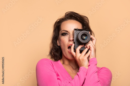 Portrait of excited girl photographer photographing with photo camera beige background, photography © be free