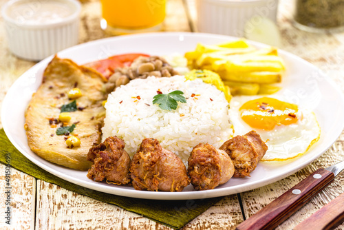 plate with typical Brazilian meal, sausage and fried chicken, rice with beans and salad, farofa and fried egg
