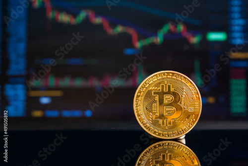 Close-up of a golden Bitcoin on a dark reflective surface